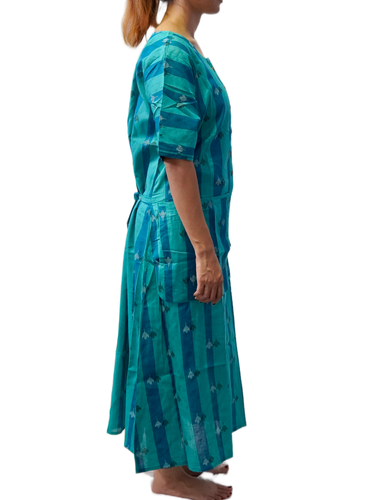 Woman wearing a teal patterned dress on a white background with side agle